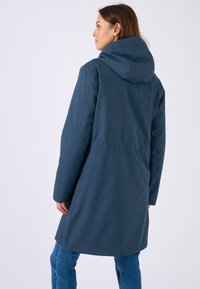 Cappotto lungo con cappuccio di colore blu navy, realizzato in materiale liscio, con vita arricciata e tasche laterali, dalla silhouette dritta.