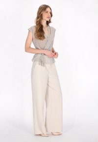 Leichtes, gemustertes Wickeltop in Beige und Grau, kombiniert mit weit geschnittenen cremefarbenen Hosen. Glatter Stoff mit gebundenem Taillenschnitt.