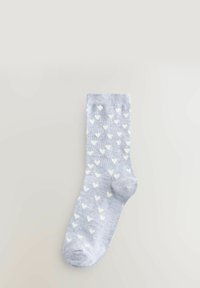 Helleblaue Socke aus weichem Stoff mit einem Muster aus kleinen weißen Herzen. Das Design ist am Bündchen gerippt und ansonsten glatt.
