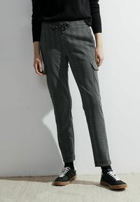Pantaloni in bianco e nero con motivo a spina di pesce, dotati di vita elastica e cordoncino, con tasche laterali e design a gamba affusolata.