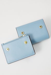 Light blue leather wallet with gold-tone hardware. Features a zippered compartment and two snap buttons, smooth texture, rectangular shape.