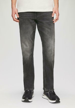 Zwarte jeans van denim met een rechte pasvorm, voorzien van een vervaagde afwerking en subtiele slijtageplekken. Draagt met zwarte sportschoenen.