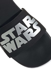 Musta liukusandaali tekstuurinauhalla, jossa on hopeinen teksti "STAR WARS" edessä. Littea pohja on sileä ja kestävä.