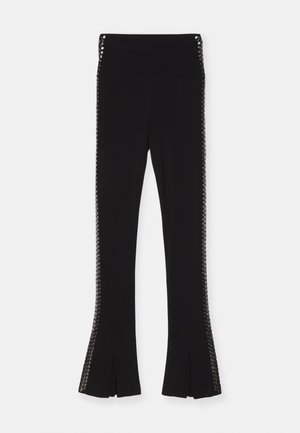 Black flared pants with a smooth texture, featuring decorative hardware on both sides and slits at the hem.