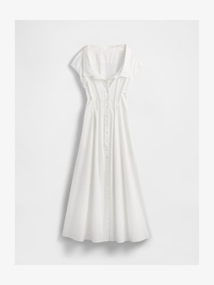 Vestido branco de botão, feito de algodão leve. Apresenta mangas curtas estilo capa, colarinho e uma saia rodada com costuras verticais.