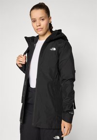 Black waterproof jacket with a hood, featuring a front zipper, adjustable waist, and logo accents on the chest and cuff.