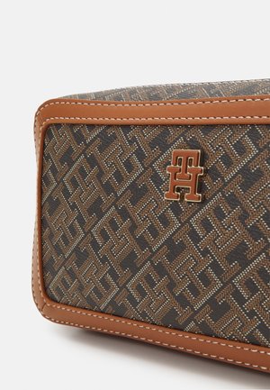 Sac à main marron à motifs présentant un design monogrammé texturé, des accents en cuir marron et un logo doré sur le devant.