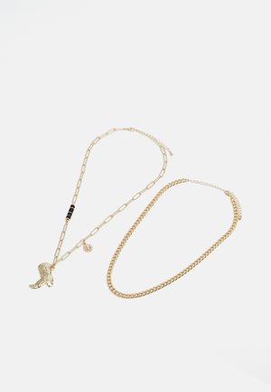 Gold-tone necklace featuring a mix of chain links, a boot pendant, black beads, and a floral charm, showcasing varied textures and shapes.
