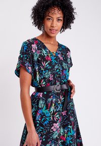 Blumenkleid mit schwarzem Hintergrund, das lebendige Farben, kurze Ärmel, einen V-Ausschnitt und eine taillierte Taille mit einem dekorativen Gürtel besitzt.