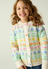 Mehrfarbiger cardigan mit floralem Muster und gerippten Kanten, ausgestattet mit rosa, blauen und gelben Knöpfen. Weiches Strickmaterial mit cremiger Basis.