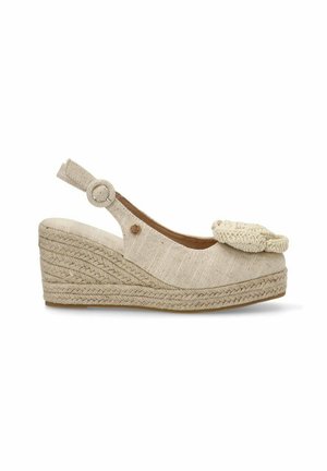 Cuña de esparto beige con una suela de yute trenzado. Presenta un upper de tela, una correa elástica en el tobillo y una flor de punto decorativa en la puntera.