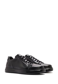 Black leather sneakers featuring a smooth texture, rounded toe, lace-up closure, and a glossy black sole.