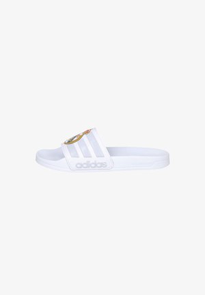 Sandalia tipo slide blanca de Adidas con tres rayas y un logo del Real Madrid en la correa, con el logotipo de Adidas en relieve en el lateral.
