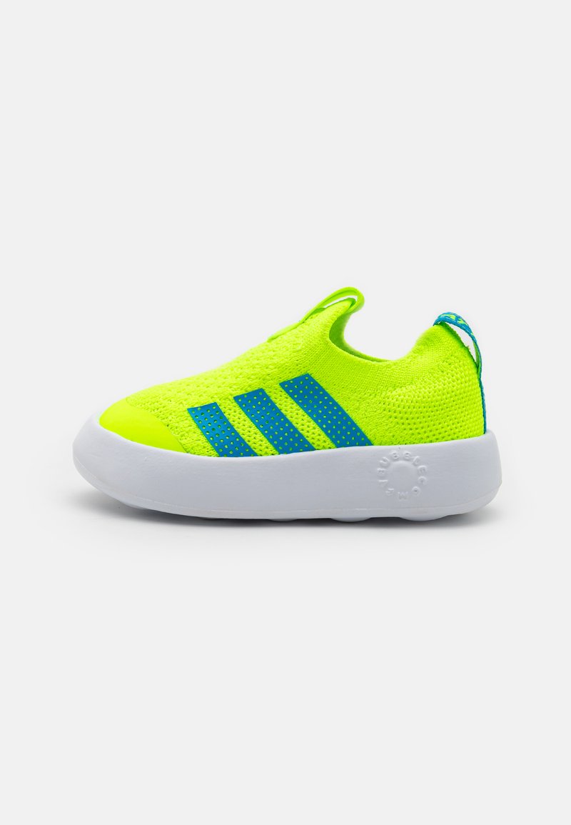Neon yellow slip-on sneakers with blue accents, knitted upper, white rubber sole, and three blue stripes on the side.