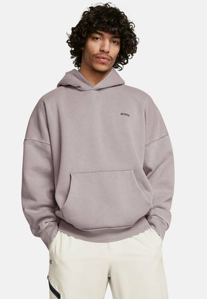 Felpa viola chiaro con cappuccio, dotata di tasca frontale e polsini a costine, realizzata in materiale morbido, indossata con pantaloni di colore chiaro.