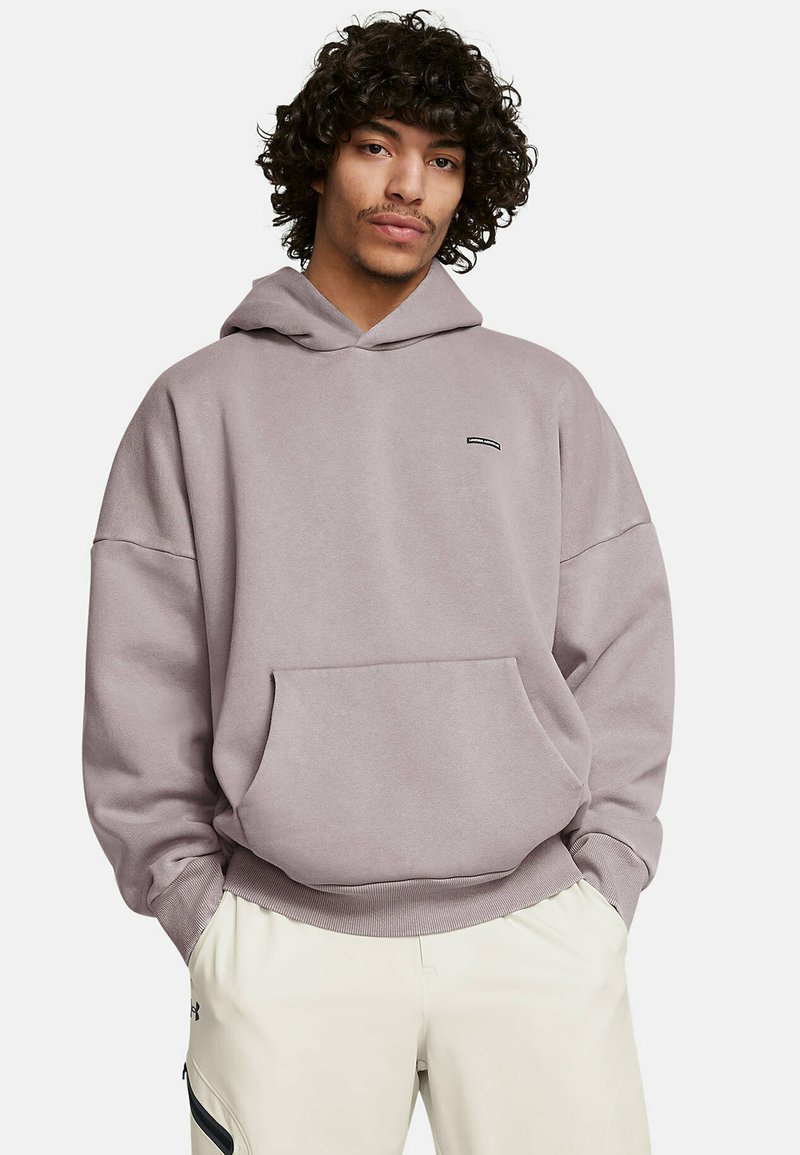 Felpa viola chiaro con cappuccio, dotata di tasca frontale e polsini a costine, realizzata in materiale morbido, indossata con pantaloni di colore chiaro.