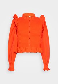 Blusa rossa corta con corpino arricciato, maniche voluminose, chiusura con bottoni e orlo frastagliato. Realizzata in tessuto leggero.