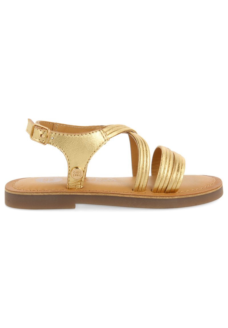 Sandalia de cuero dorado con múltiples diseños de correas, hebilla ajustable en el tobillo, plantilla acolchada y suela de goma marrón. Textura suave y líneas limpias.
