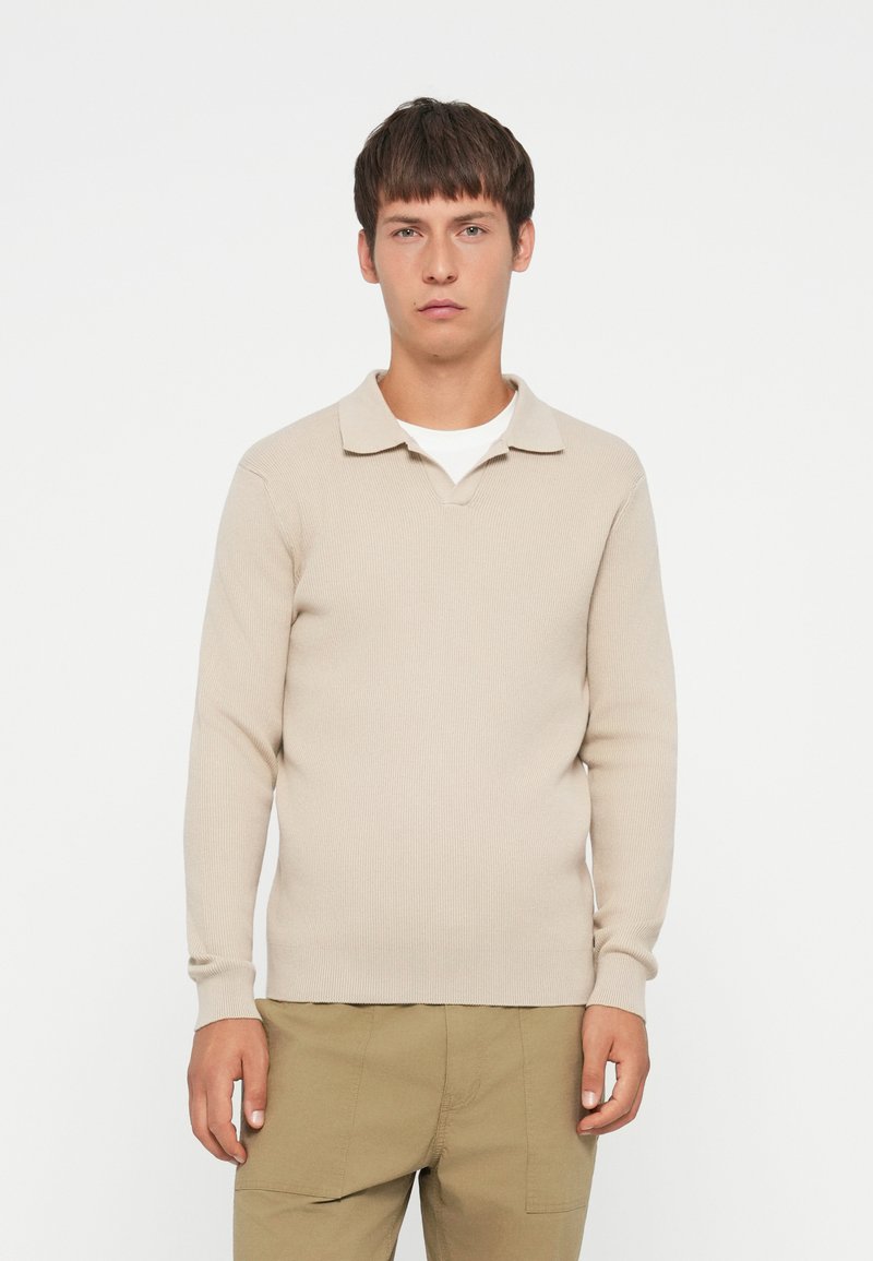 Beige geribbelde longsleeve polo trui met een kraaghals, voorzien van een gestructureerd oppervlak en een getailleerde pasvorm.