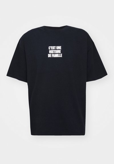 Sort t-shirt i bomuld med løs pasform. Udsmykket med hvid tekst, der står "C'EST UNE HISTOIRE DE FAMILLE" centreret på forsiden.