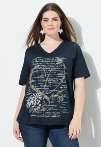 Camiseta de algodón azul marino con cuello en V y mangas cortas, que presenta un patrón floral blanco y texto impreso en dorado, creando un diseño texturizado.