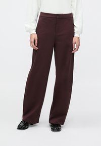 Vinrøde bukser med vide ben lavet af et glat stof, med en tætsiddende talje og uden synlige lommer eller pynt.