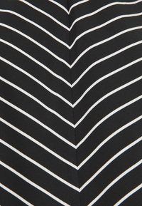 Mustaa kangasta, jossa on valkoiset vaakasuorat raidat, jotka luovat sahalaitakuviota. Sileä tekstuuri ja symmetrinen, rohkea muotoilu.