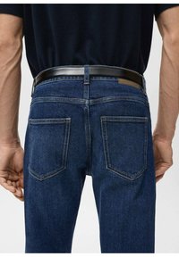 Vaqueros de mezclilla azul oscuro con corte recto, dos bolsillos traseros y un cinturón de cuero negro. Detalles de costura visibles realzan el diseño.