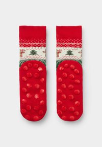 Rote Socken mit einem festlichen Muster, das Bäume und Zuckerstangen zeigt, mit strukturierten roten Grip-Punkten an den Sohlen für bessere Haftung.