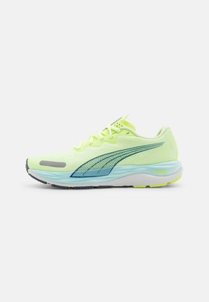 Zapatillas de running ligeras en un brillante color amarillo con acentos en azul. Presentan una parte superior de malla, una suela acolchada y una textura detallada para mejorar el agarre.