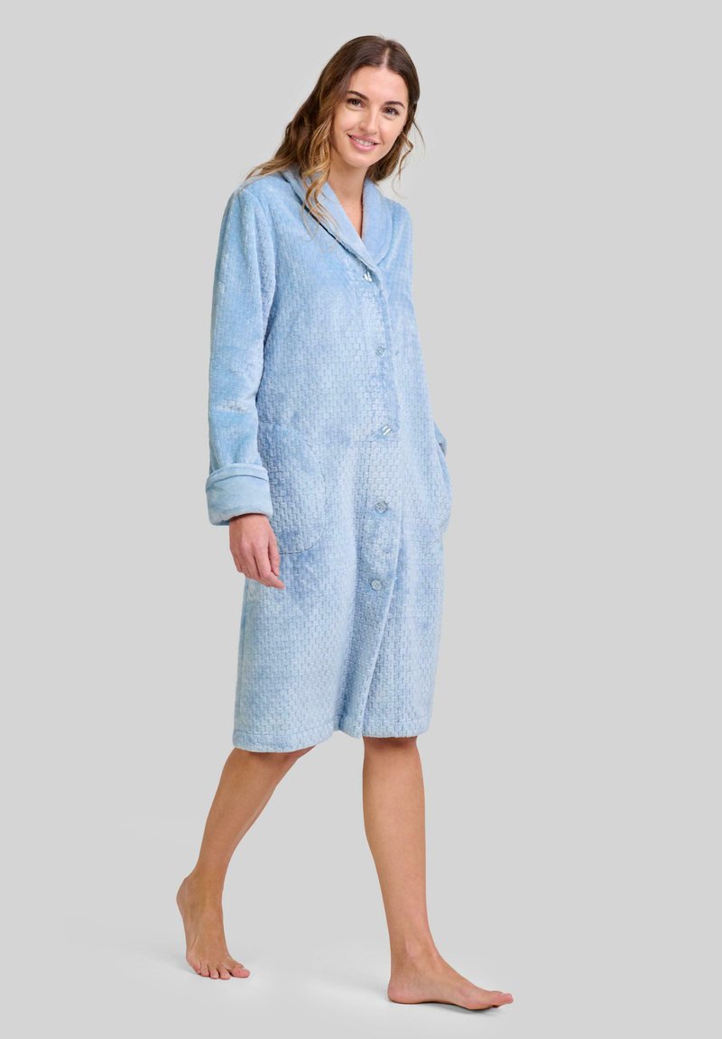 Bata de baño texturada de color azul claro con cuello, botones al frente y bolsillos laterales; presenta mangas largas y un diseño hasta la rodilla.