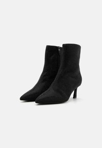 Botines negros con punta afilada, fabricados en un tejido texturizado, que cuentan con una cremallera lateral y un tacón alto y delgado.
