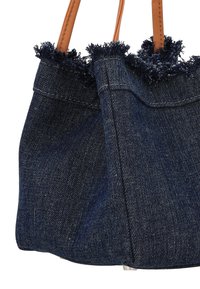 Denim boodschappentas met rafelige bovenrand, donkerblauwe kleur en bruine leren handvatten. Voorzien van stevige stiksels en een gestructureerde vorm.