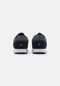 Sneaker blu navy realizzati in una combinazione di pelle liscia e scamosciata, con una suola intermedia bianca e un piccolo dettaglio del logo sul retro.