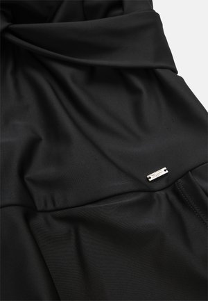 Zwarte, gladde stof met een verzameld ontwerp, voorzien van een klein metallic accentlabel. Zachte textuur met een subtiele glans.