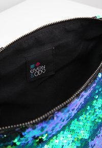 Borsa con paillettes con una sfumatura di blu e verde, chiusura con zip e un interno in tessuto nero con etichetta del marchio.
