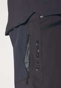 Los pantalones cortos de ciclismo negros cuentan con bolsillos con cremallera y acentos reflectantes, fabricados con una tela duradera y texturizada con un diseño ajustado.