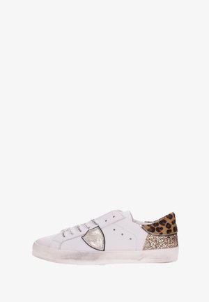 Zapatilla blanca de corte bajo con emblema de escudo plateado, cuello del talón con estampado de leopardo y panel trasero con purpurina dorada.