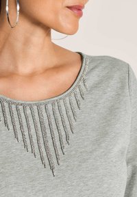 Grauer Sweatshirt mit Rundhalsausschnitt, verziert mit silbernem Fransen-Detail aus Strasssteinen, strukturiertem Stoff und entspannter Passform.