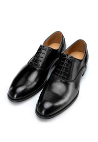 Chaussures habillées en cuir noir avec un bout pointu, six œillets pour les lacets et une finition lisse. Présente un accent cousu le long du bord.