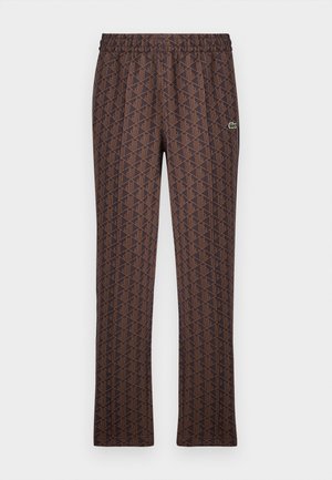 Pantalons à motifs marron avec une ceinture élastique, arborant un design géométrique dans une teinte plus foncée et un petit logo vert en accent.