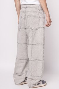 Lichtgrijze, oversized denim broek met een patchworkontwerp, gekenmerkt door grote zakken en een relaxed fit. De stof heeft een zachte, licht gestructureerde afwerking.