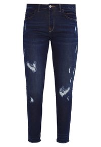 Jeans ajustados de denim azul oscuro con áreas desgastadas y dobladillos deshilachados. Presenta cinco bolsillos y un cierre de botón.