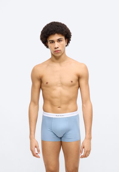 Boxers bleu clair avec une ceinture blanche portant le nom de la marque. Tissu lisse, coupe ajustée et design mi-cuisse.