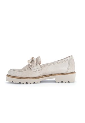 Beige ruskindsløber med chunky sål og dekorativt knudet remdetalje, vist i sidemodel på hvid baggrund.