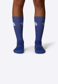Calcetas azules hasta la rodilla con textura acanalada, que presentan acentos de logo en blanco y una banda superior de contraste. Acabado suave y forma ajustada.