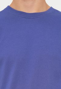 Lila pamut póló kerek nyakkivágással és rövid ujjakban, sima, egyenletes textúrával, látható minták vagy dizájnok nélkül.