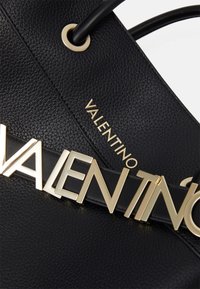 Schwarze Lederhandtasche mit strukturiertem Oberflächen, goldener Hardware und auffälliger goldener "VALENTINO"-Schriftzug auf einem schwarzen Riemen.
