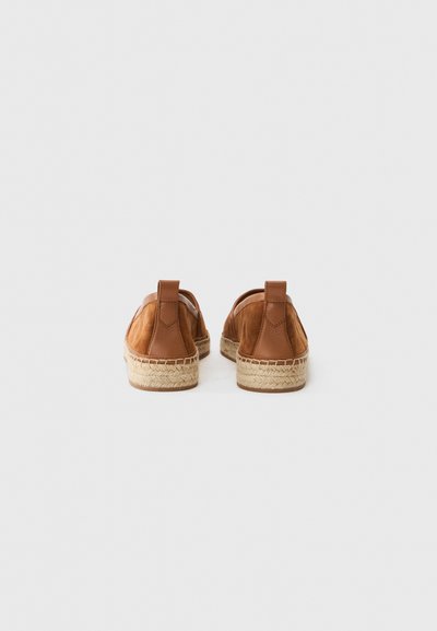 Bruna läderskor utan snörning med vävda espadrille-sulor, med en rundad design och sydda detaljer baktill.