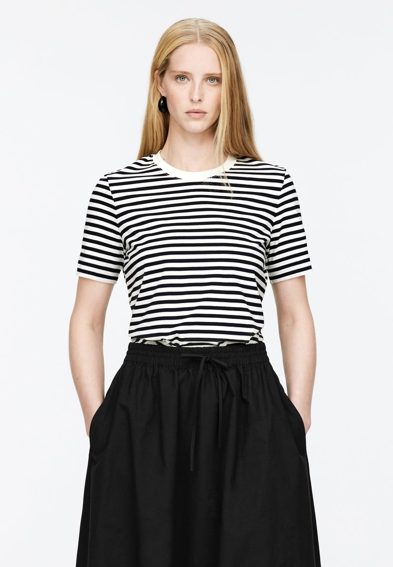 Kurzarm-T-Shirt mit schwarz-weißen Streifen und rundem Halsausschnitt, kombiniert mit einem schwarzen Rock mit elastischem Bund und seitlichen Taschen.